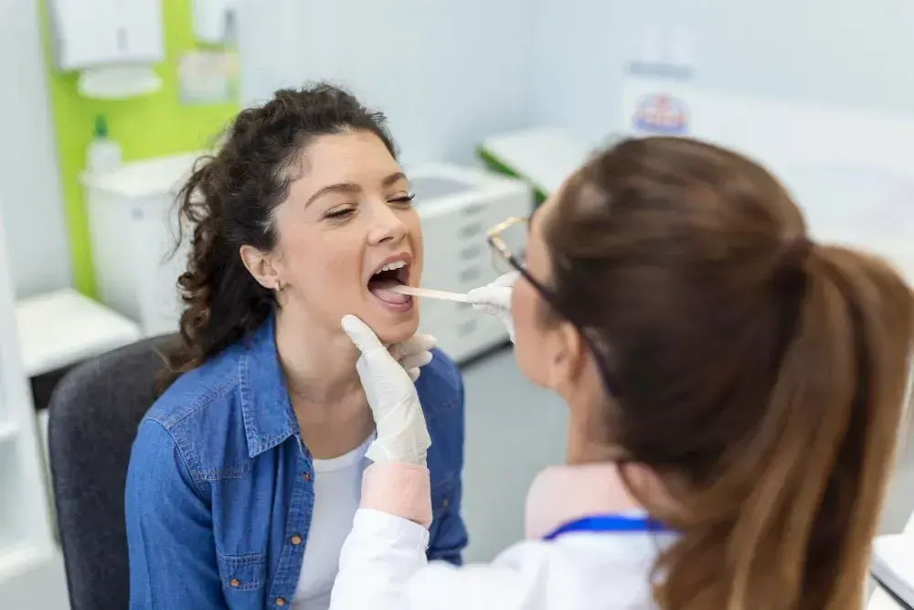 Mulher está em uma consulta médica para avaliar possíveis doenças na língua.