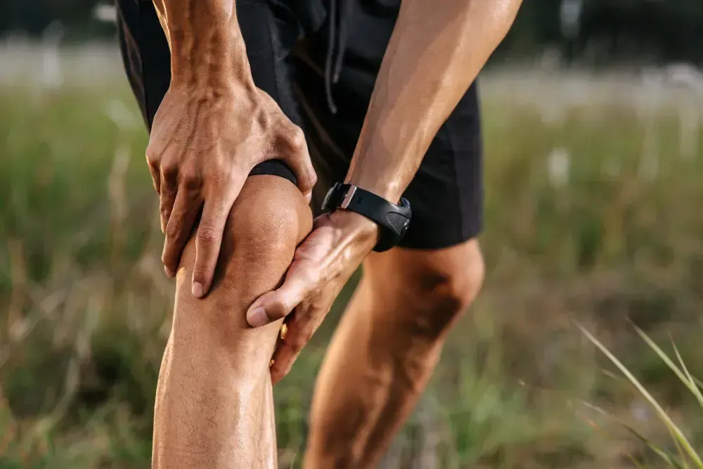 Homem sente dor no joelho ao praticar exercício físico.