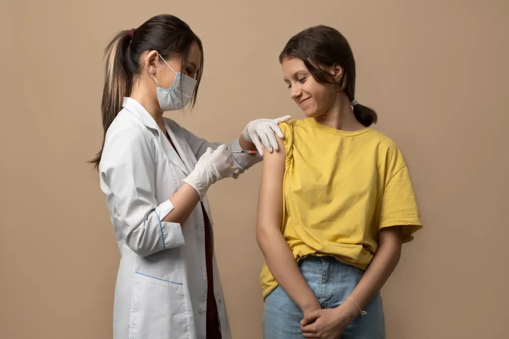 Médica aplica vacina para o HPV em adolescente.