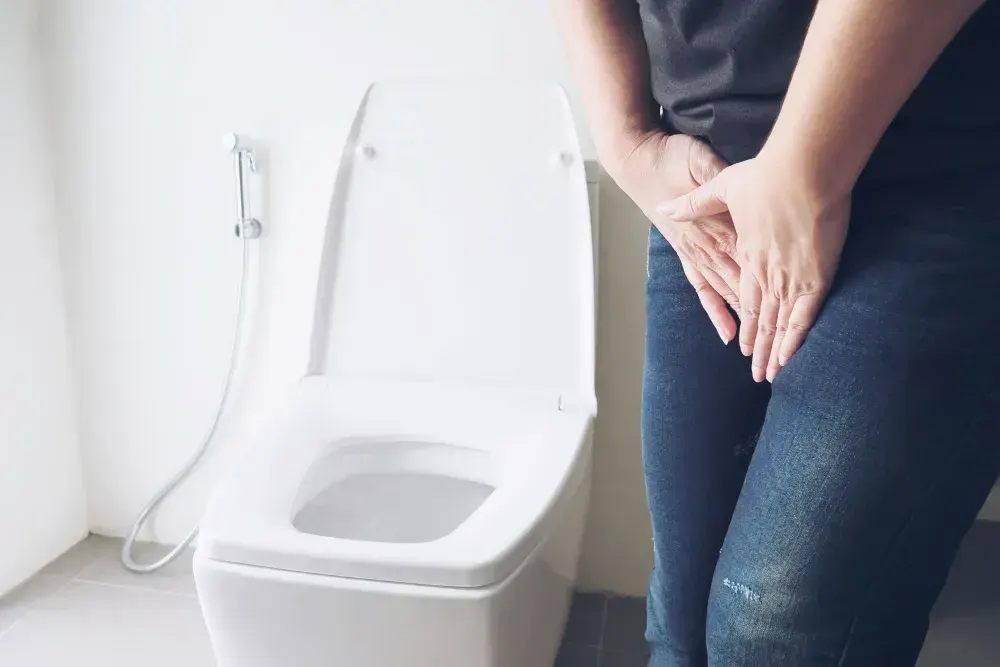 Mulher com infecção urinária está ao lado de um vaso sanitário.
