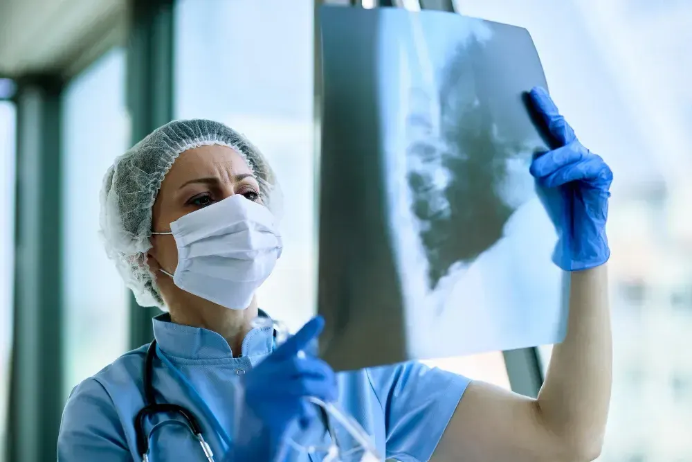 Médica avalia exames com diagnóstico de pneumonia.