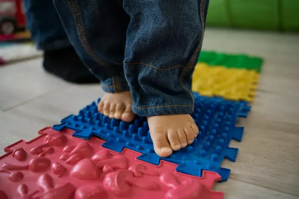 Criança está andando em um tapete sensorial ela apresenta Transtorno de Processamento Sensorial.