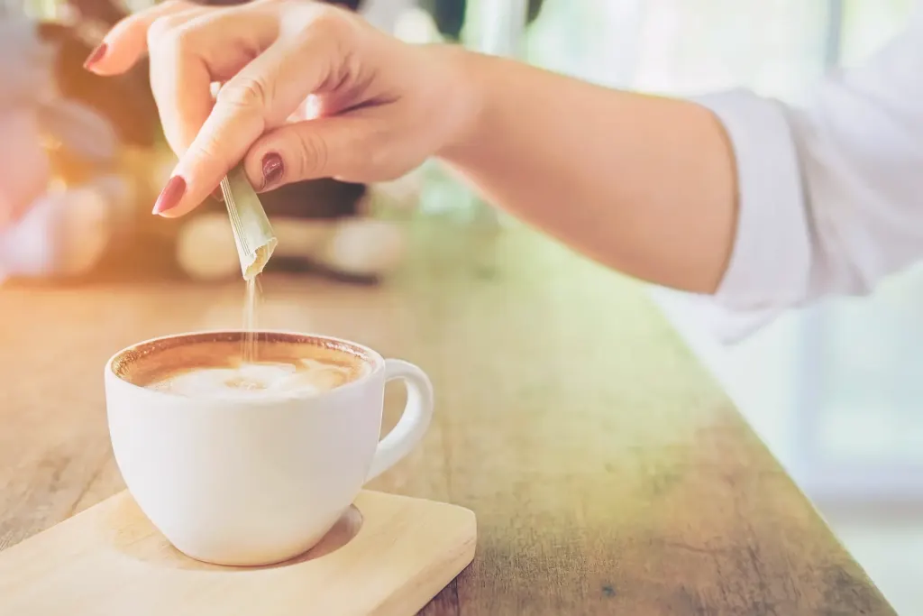 mulher usa adoçantes em uma xícara de café